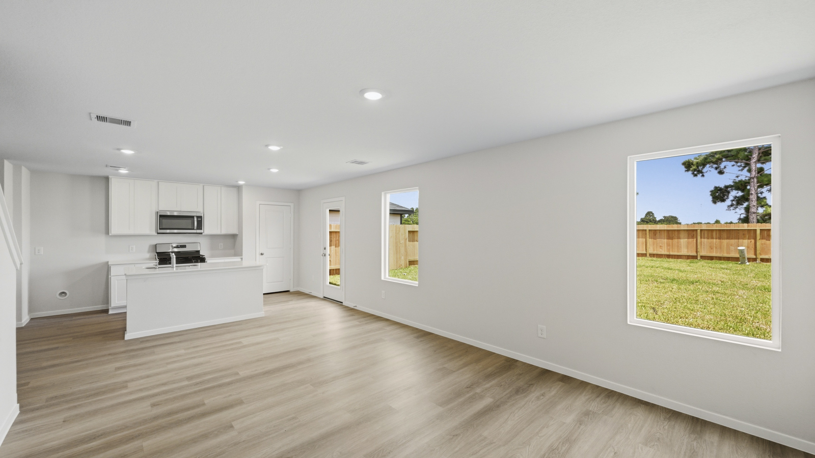 open concept living and dining area with vinyl flooring, large windows, and quartz countertops