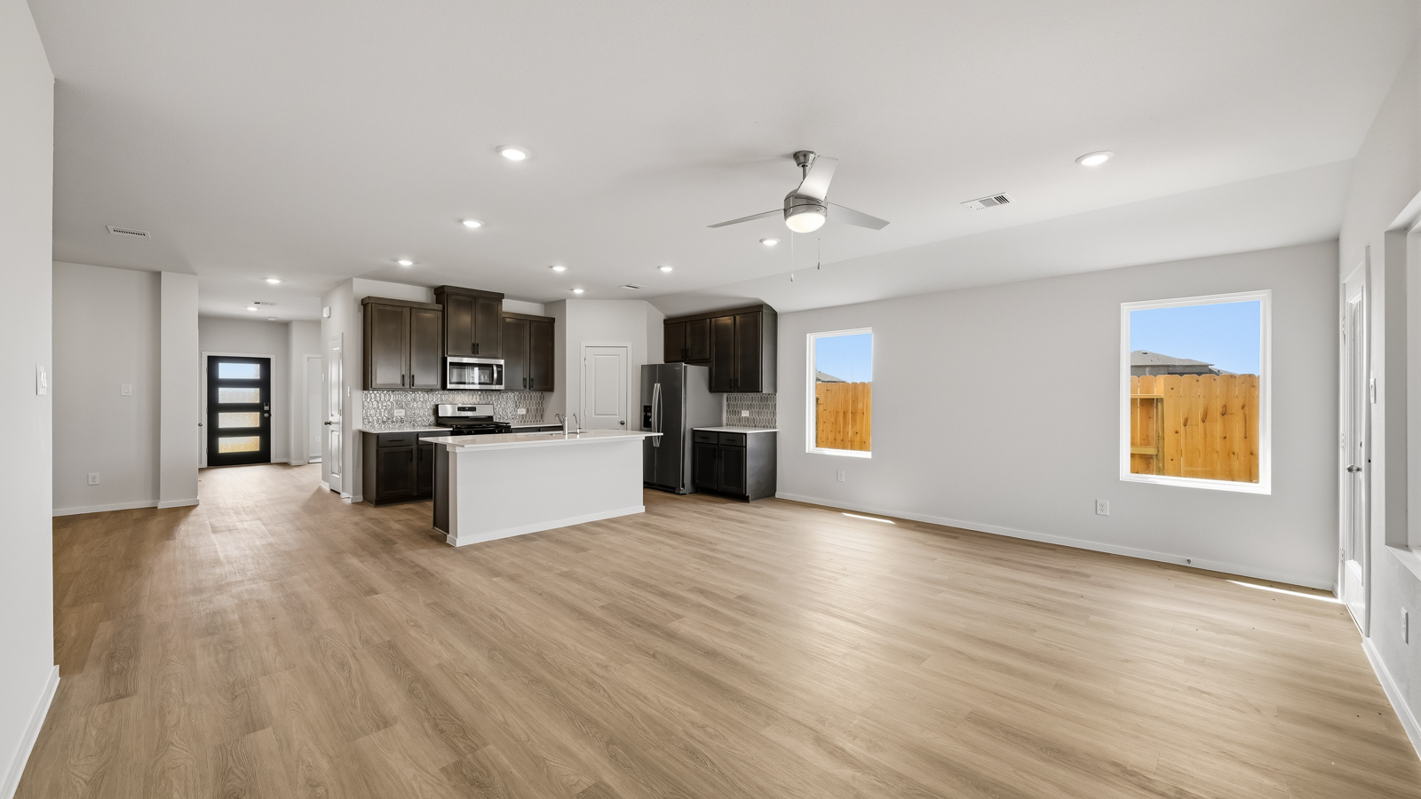 open concept living and dining area with vinyl flooring and large windows in Brookshire, TX