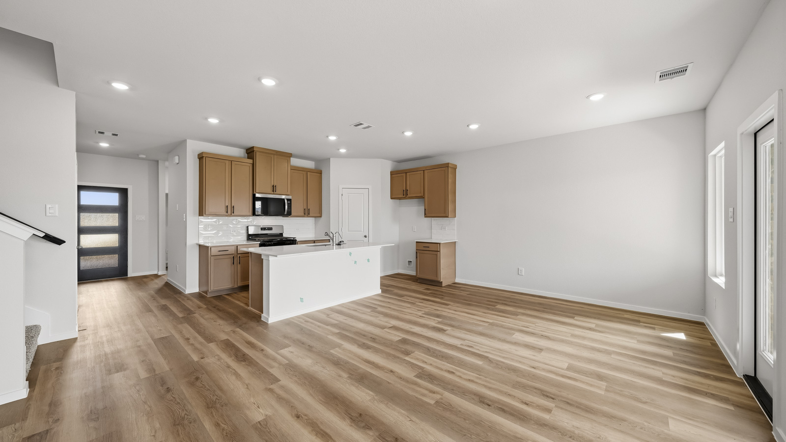 open concept living and dining area with vinyl flooring, arge windows, and quartz countertops in Brookshire, Tx