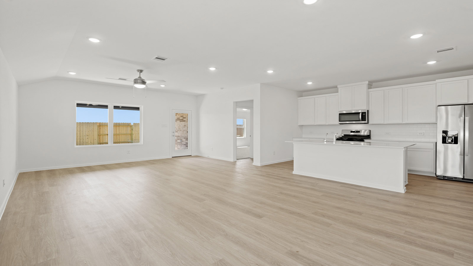 open concept livving and dining area with vinyl flooring, large windows, and quartz countertops