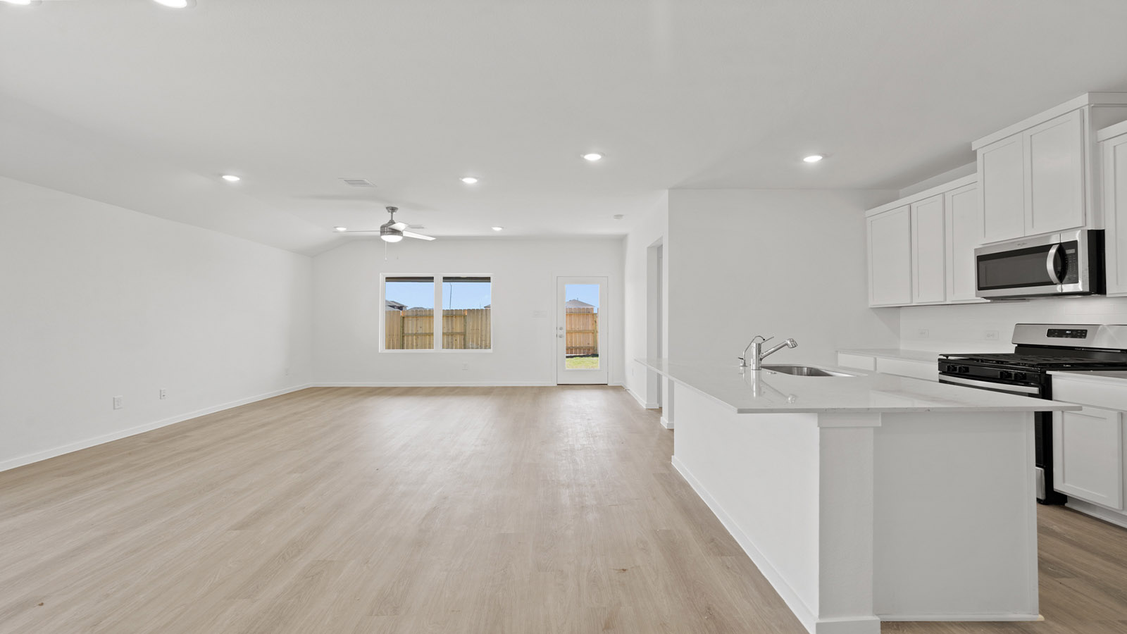 open concept livving and dining area with vinyl flooring, large windows, and quartz countertops