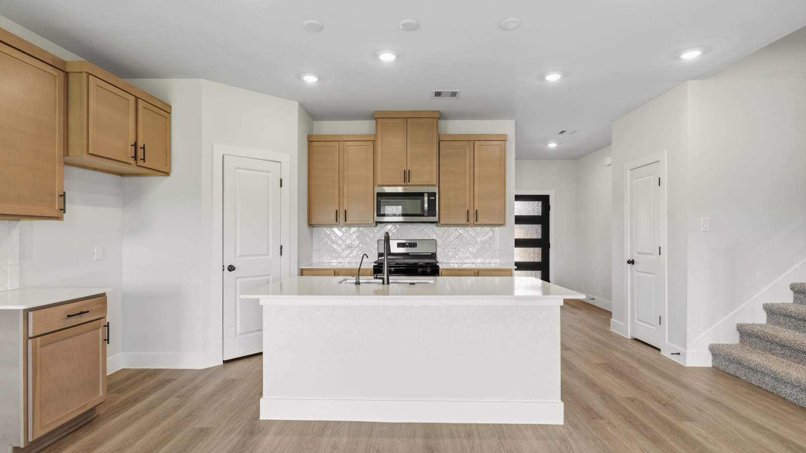 Kitchen with stainless steel appliances, quartz countertops and modern hardware and an island and vinyl floor