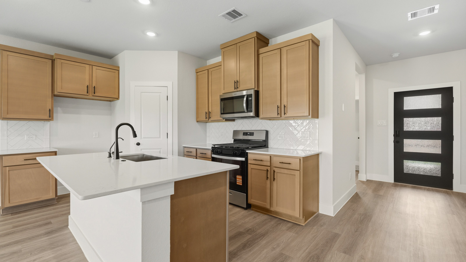 Kitchen with stainless steel appliances, quartz countertops and modern hardware and an island and vinyl floor