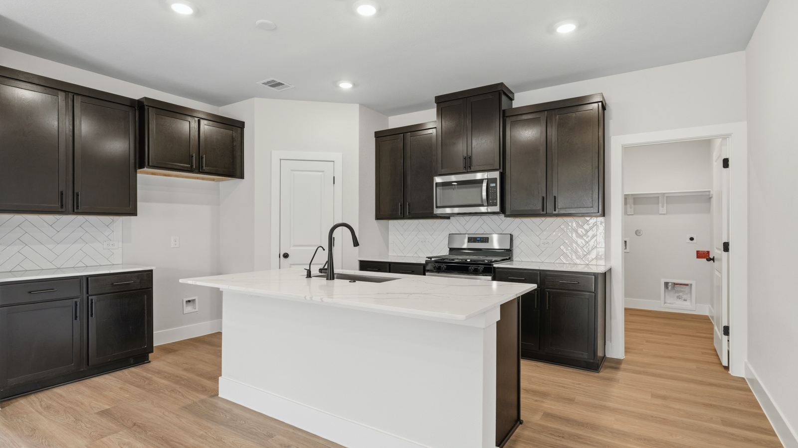 Kitchen with stainless steel appliances, quartz countertops and modern hardware and an island and vinyl floor