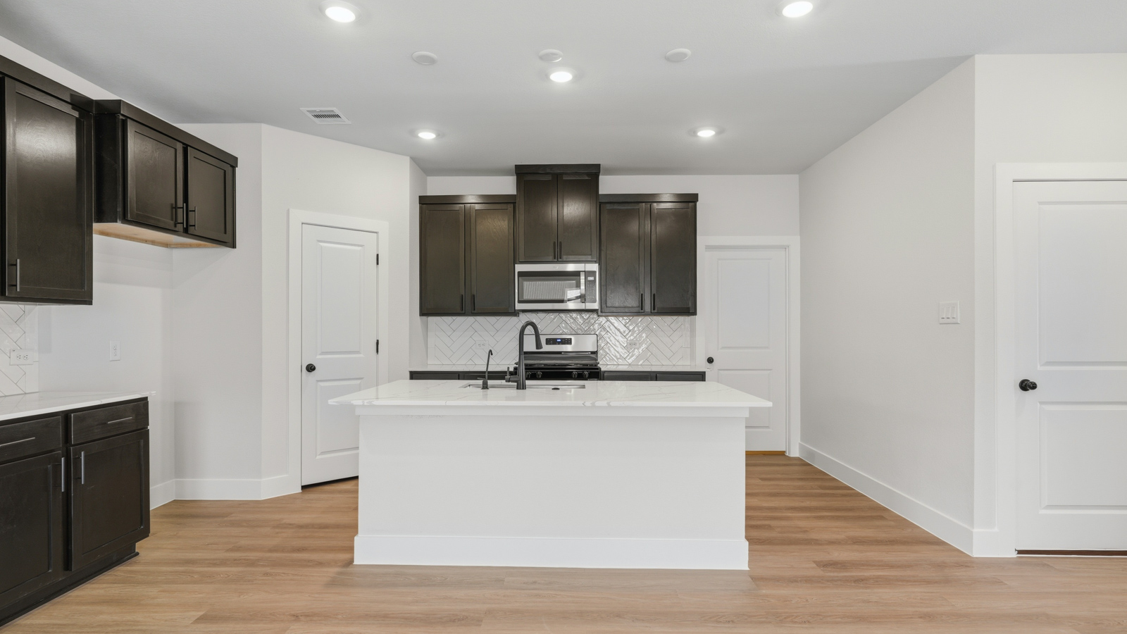 Kitchen with stainless steel appliances, quartz countertops and modern hardware and an island and vinyl floor