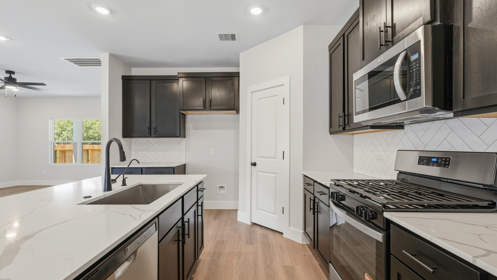 Kitchen with stainless steel appliances, quartz countertops and modern hardware and an island and vinyl floor