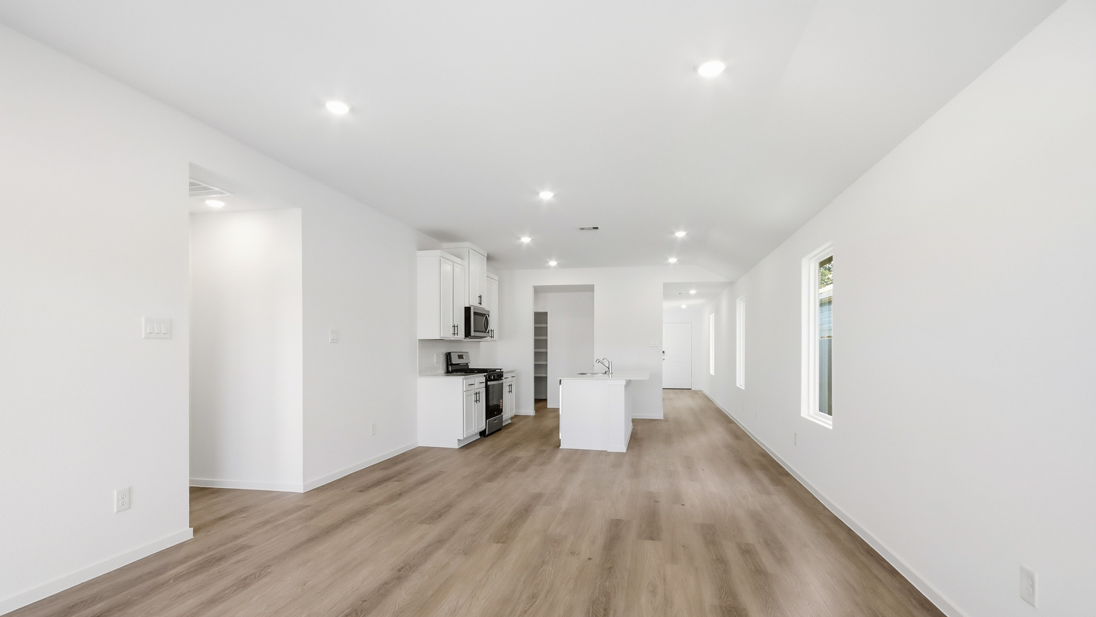 open concept living and dining area with vinyl flooring, quartz countertops, and stainless steel appliances