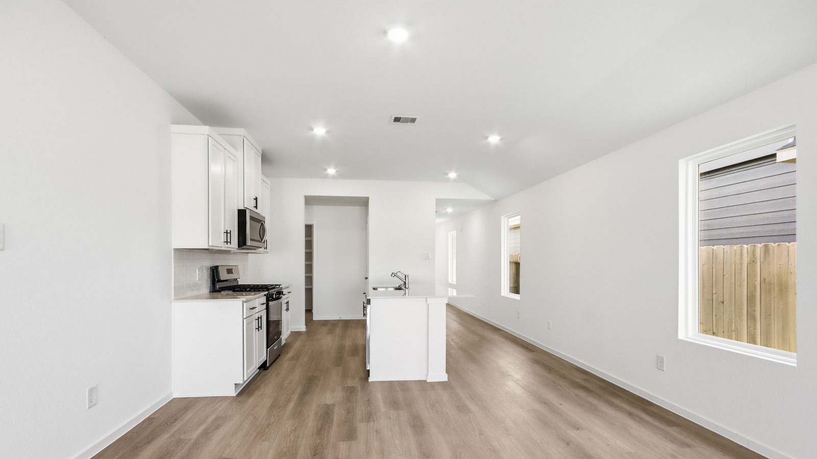 open concept living and dining area with vinyl flooring, quartz countertops, and stainless steel appliances