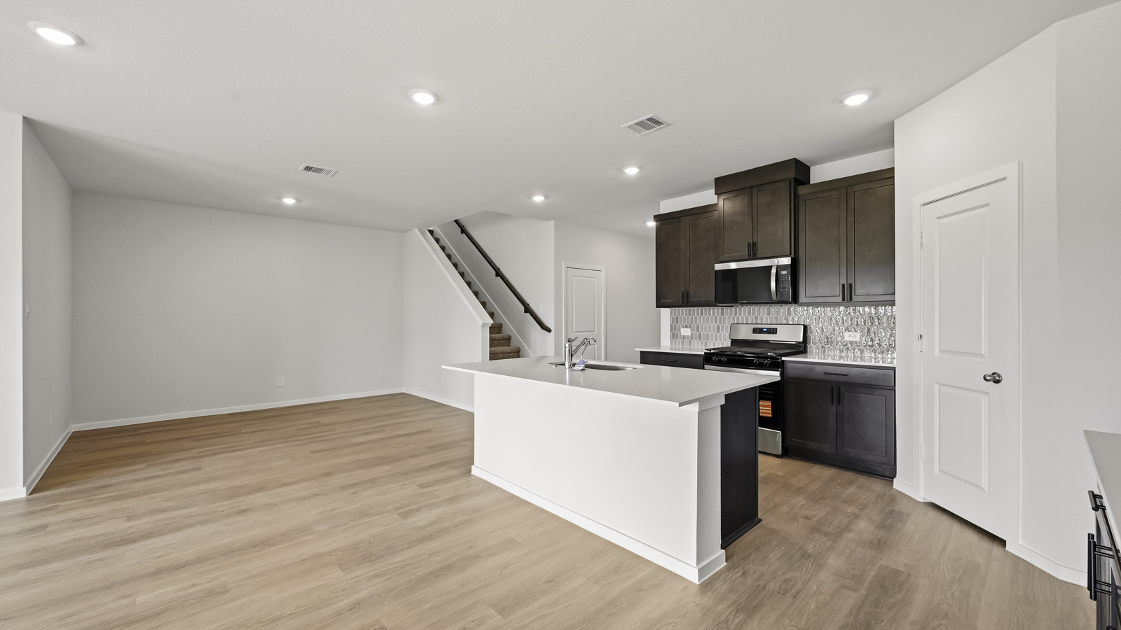 open concept living and dining area with vinyl flooring, large windows, and quartz countertops in Hockley, TX