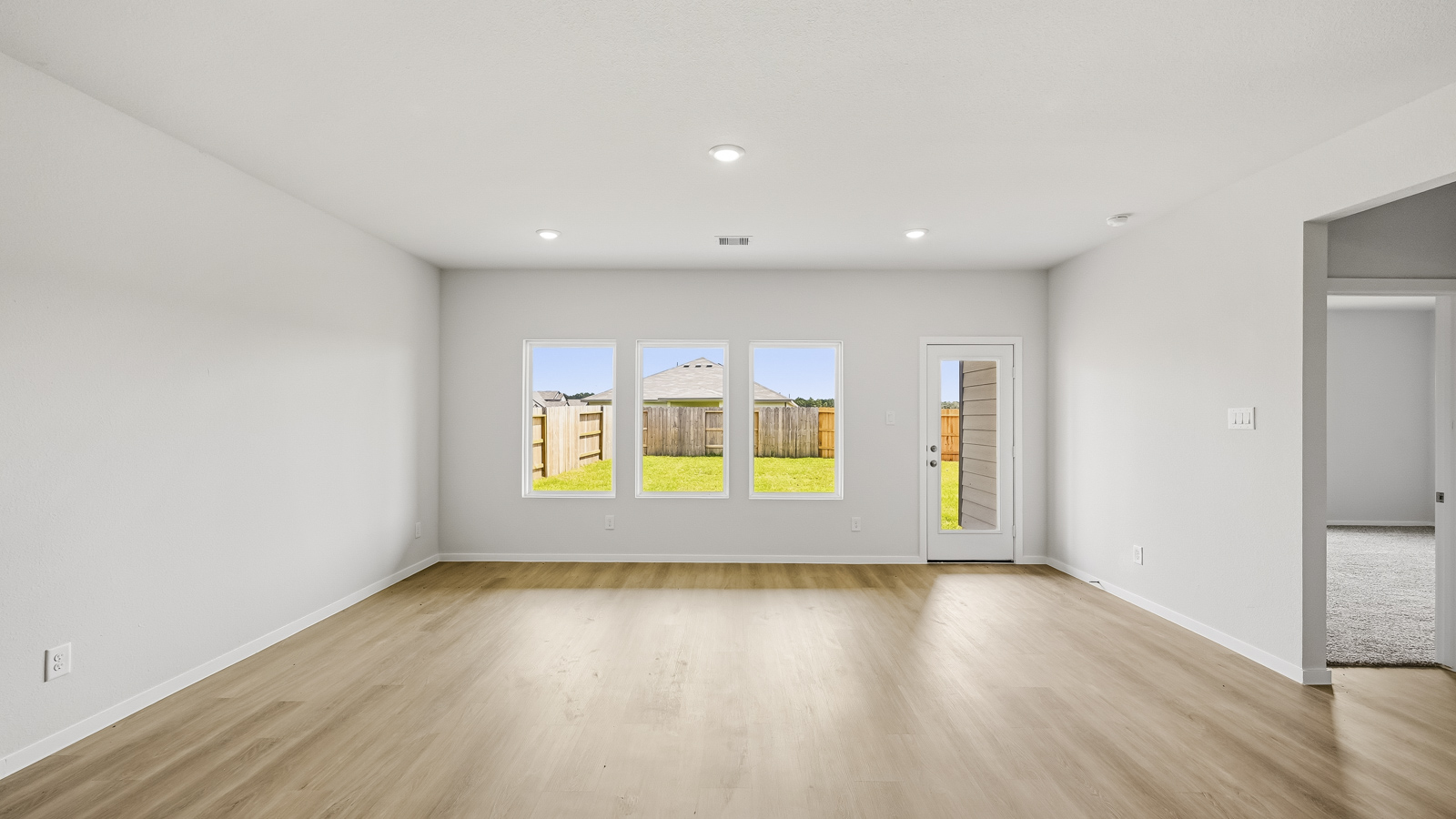 open concept living and dining area with vinyl flooring, large windows, and quartz countertops in Hockley, TX