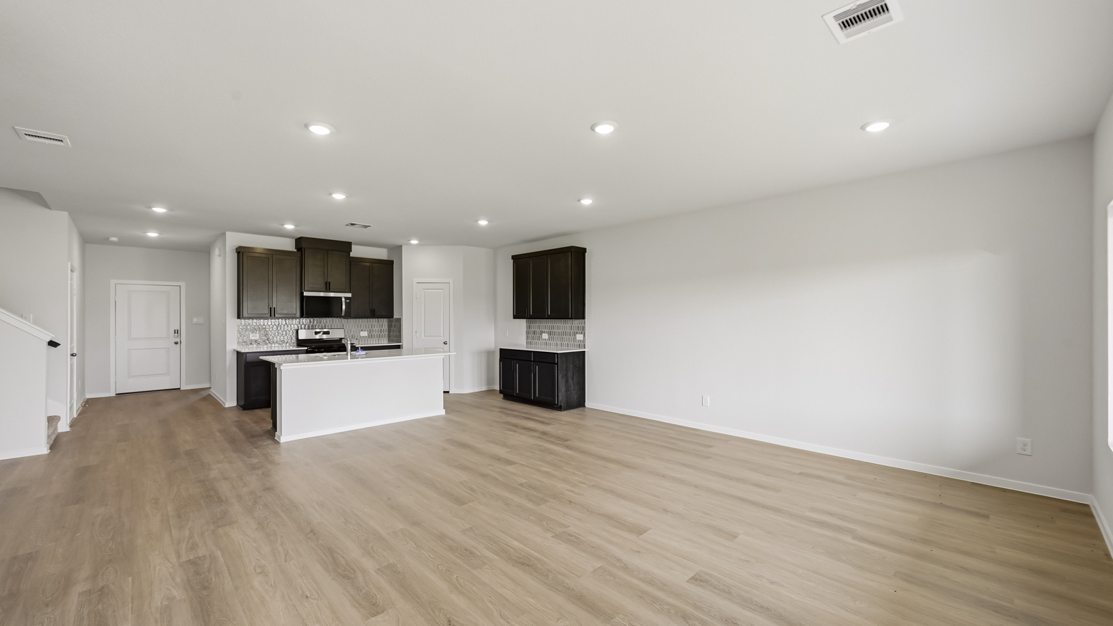 open concept living and dining area with vinyl flooring, large windows, and quartz countertops in Hockley, TX