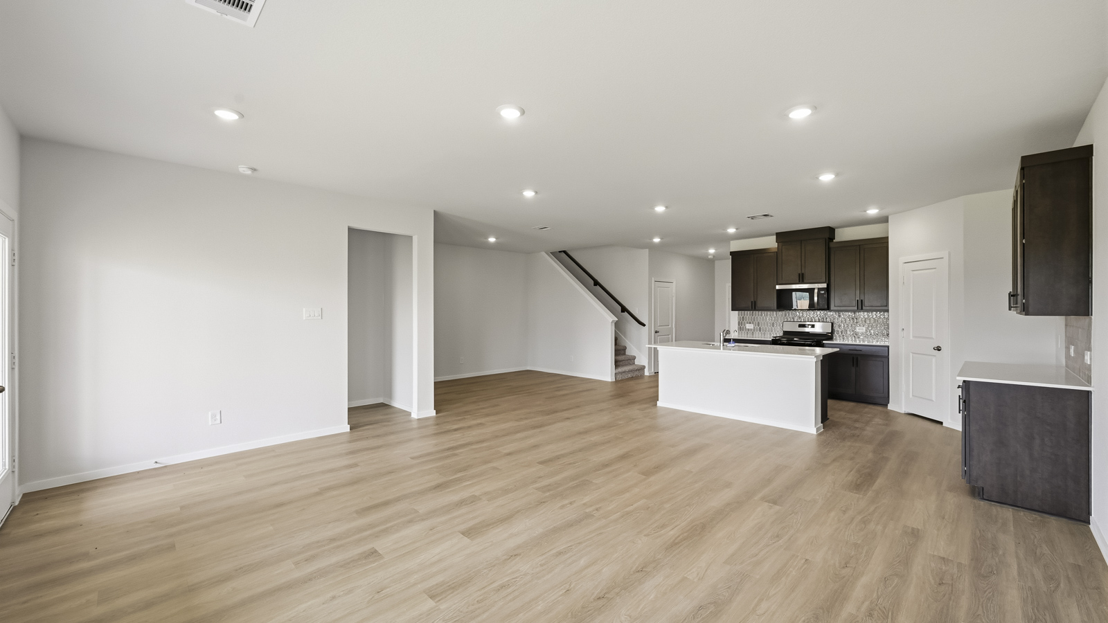 open concept living and dining area with vinyl flooring, large windows, and quartz countertops in Hockley, TX
