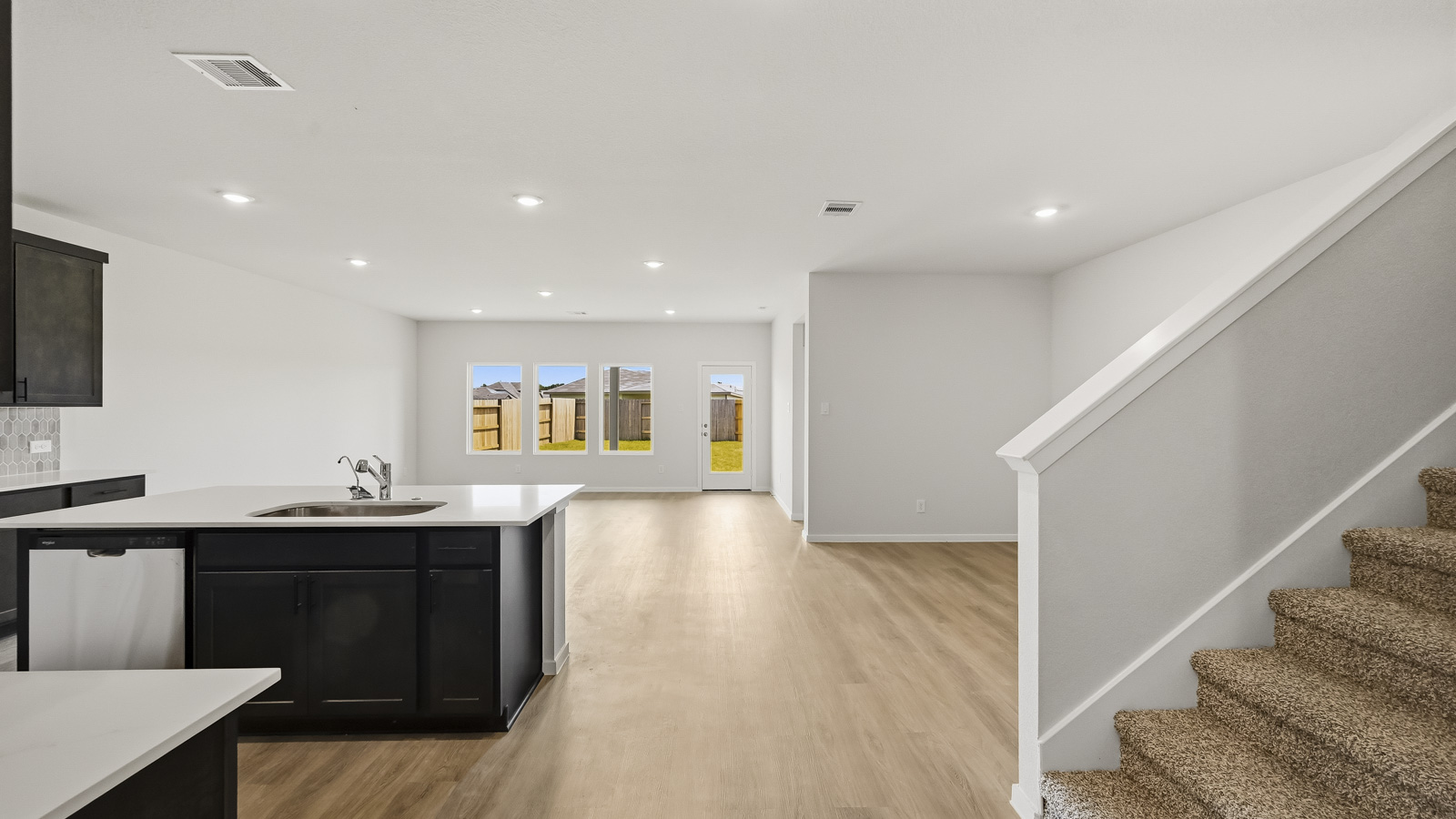 open concept living and dining area with vinyl flooring, large windows, and quartz countertops in Hockley, TX