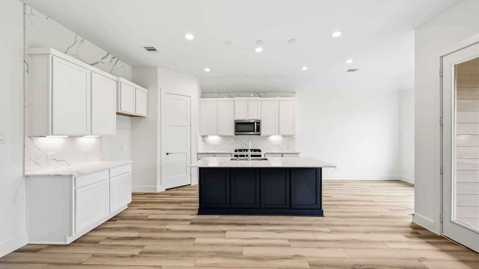 Kitchen with quartz countertops and marden hardware and an island and vinyl floor