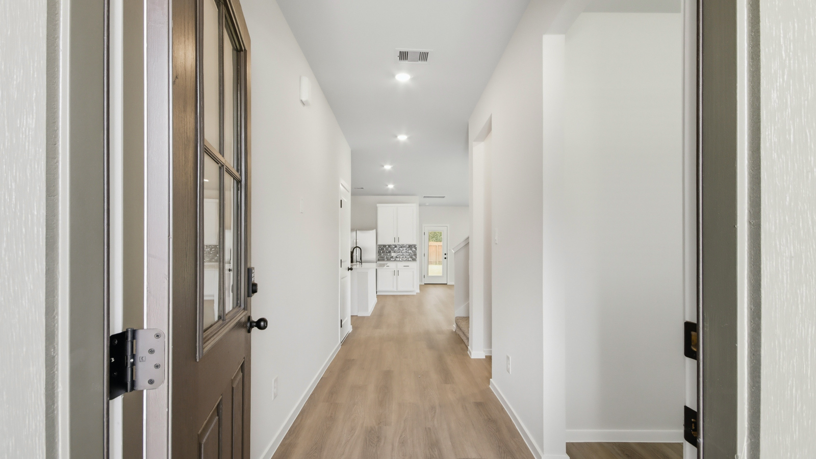 Open concept living, dining, and kitchen area with vinyl flooring and bright windows