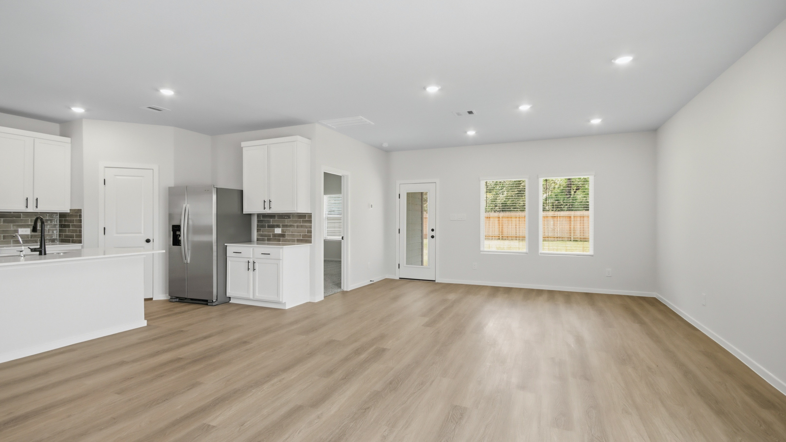 Open concept living, dining, and kitchen area with vinyl flooring and bright windows