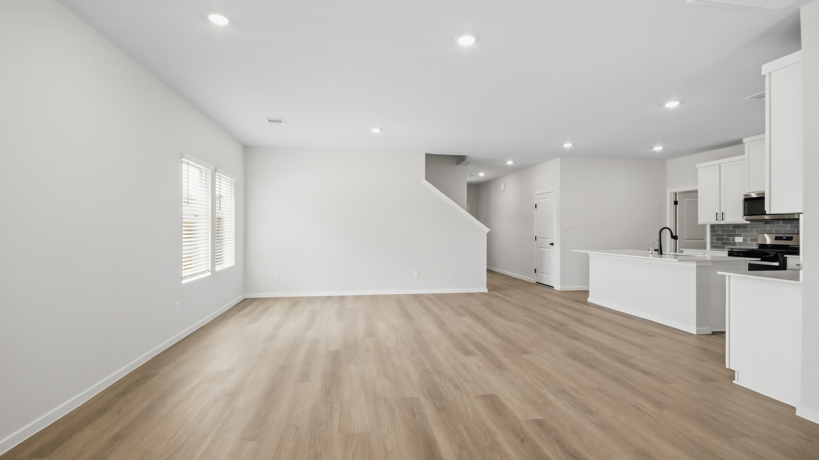 Open concept living, dining, and kitchen area with vinyl flooring and bright windows