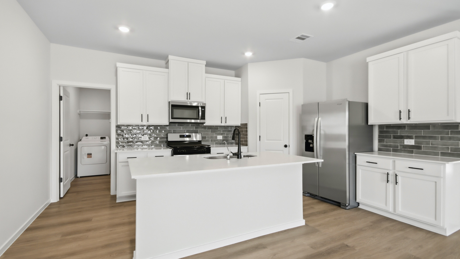 Open concept living, dining, and kitchen area with vinyl flooring and bright windows