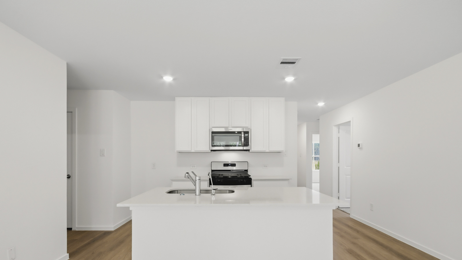 Kitchen with stainless steel appliances, quartz countertops and modern hardware and an island and vinyl floor