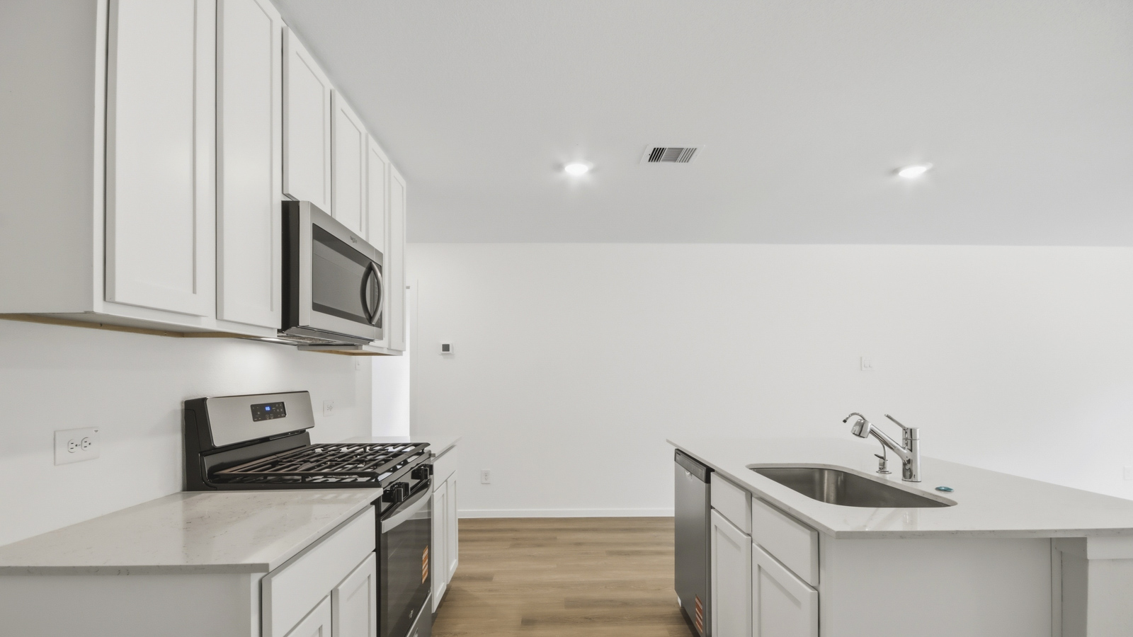Kitchen with stainless steel appliances, quartz countertops and modern hardware and an island and vinyl floor