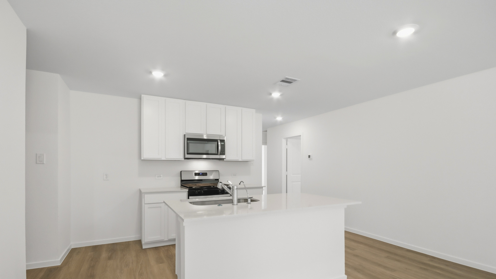 Kitchen with stainless steel appliances, quartz countertops and modern hardware and an island and vinyl floor