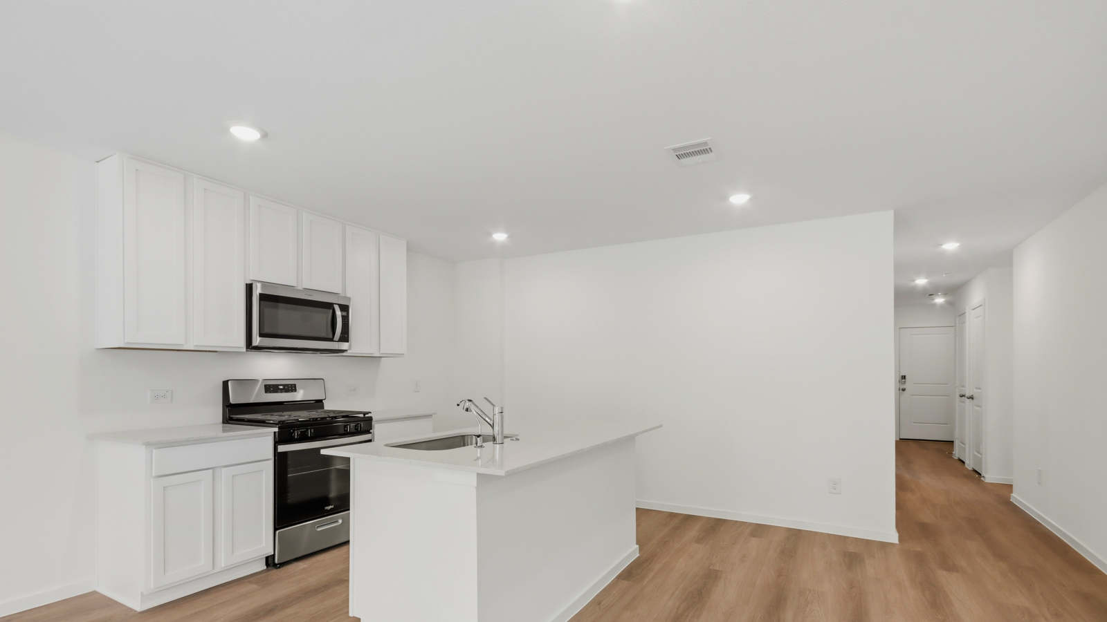 Kitchen with stainless steel appliances, quartz countertops and modern hardware and an island and vinyl floor