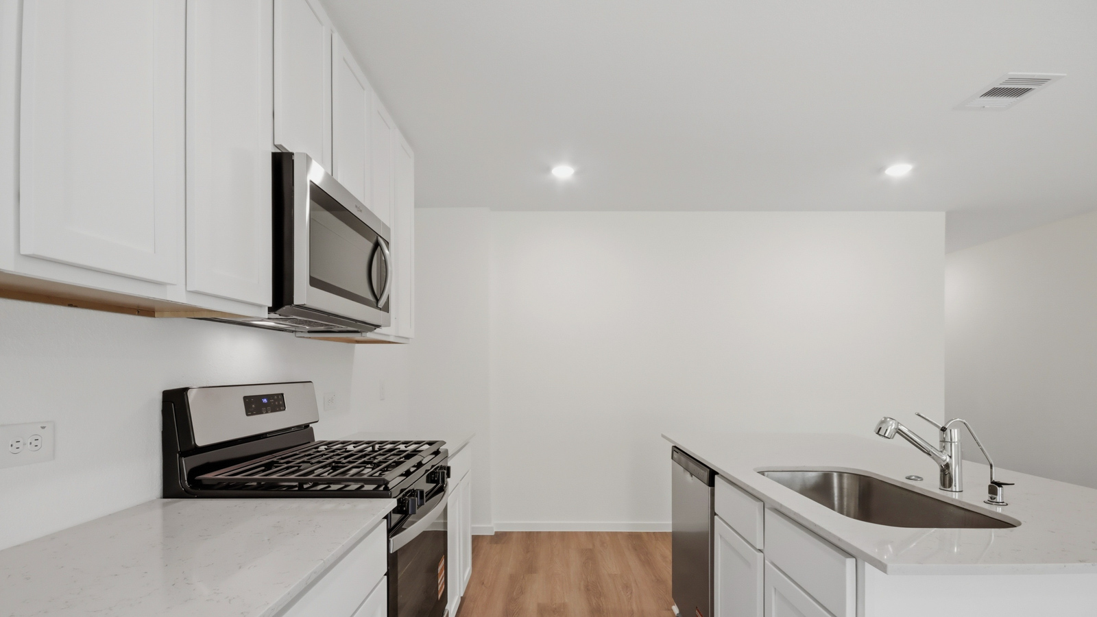 Kitchen with stainless steel appliances, quartz countertops and modern hardware and an island and vinyl floor