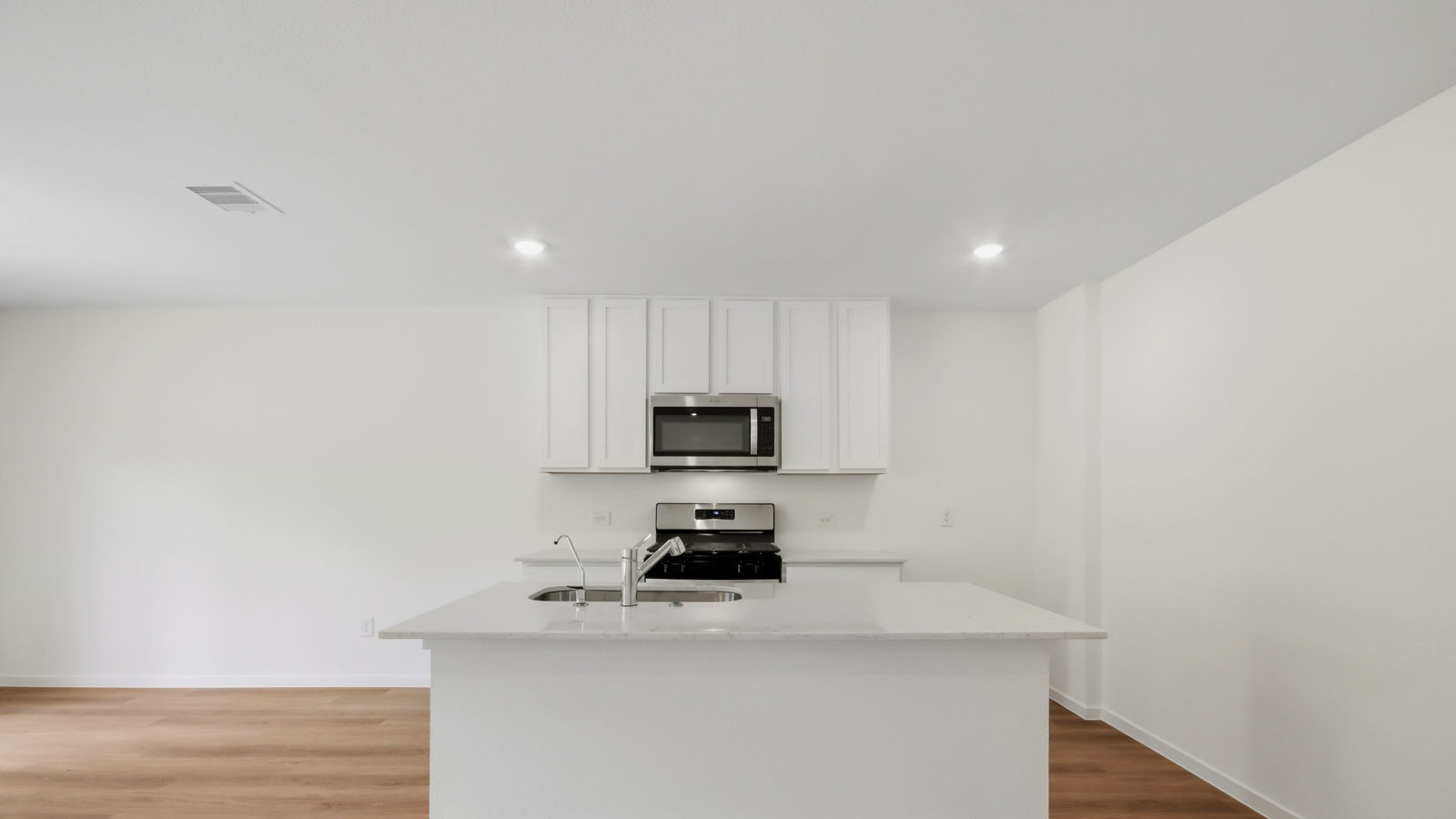 Kitchen with stainless steel appliances, quartz countertops and modern hardware and an island and vinyl floor