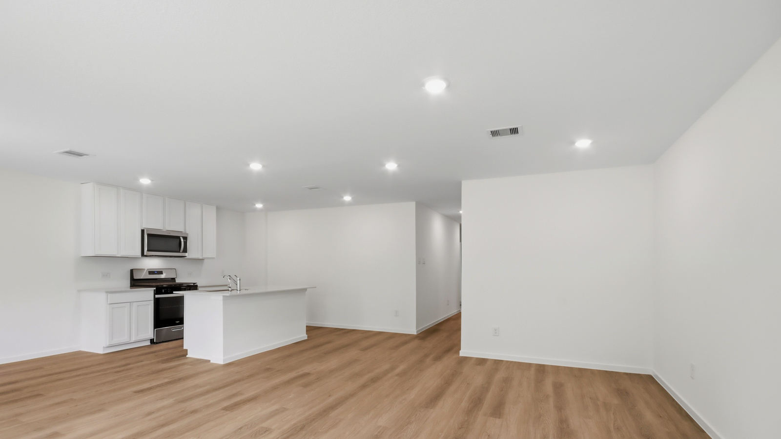 Kitchen with stainless steel appliances, quartz countertops and modern hardware and an island and vinyl floor