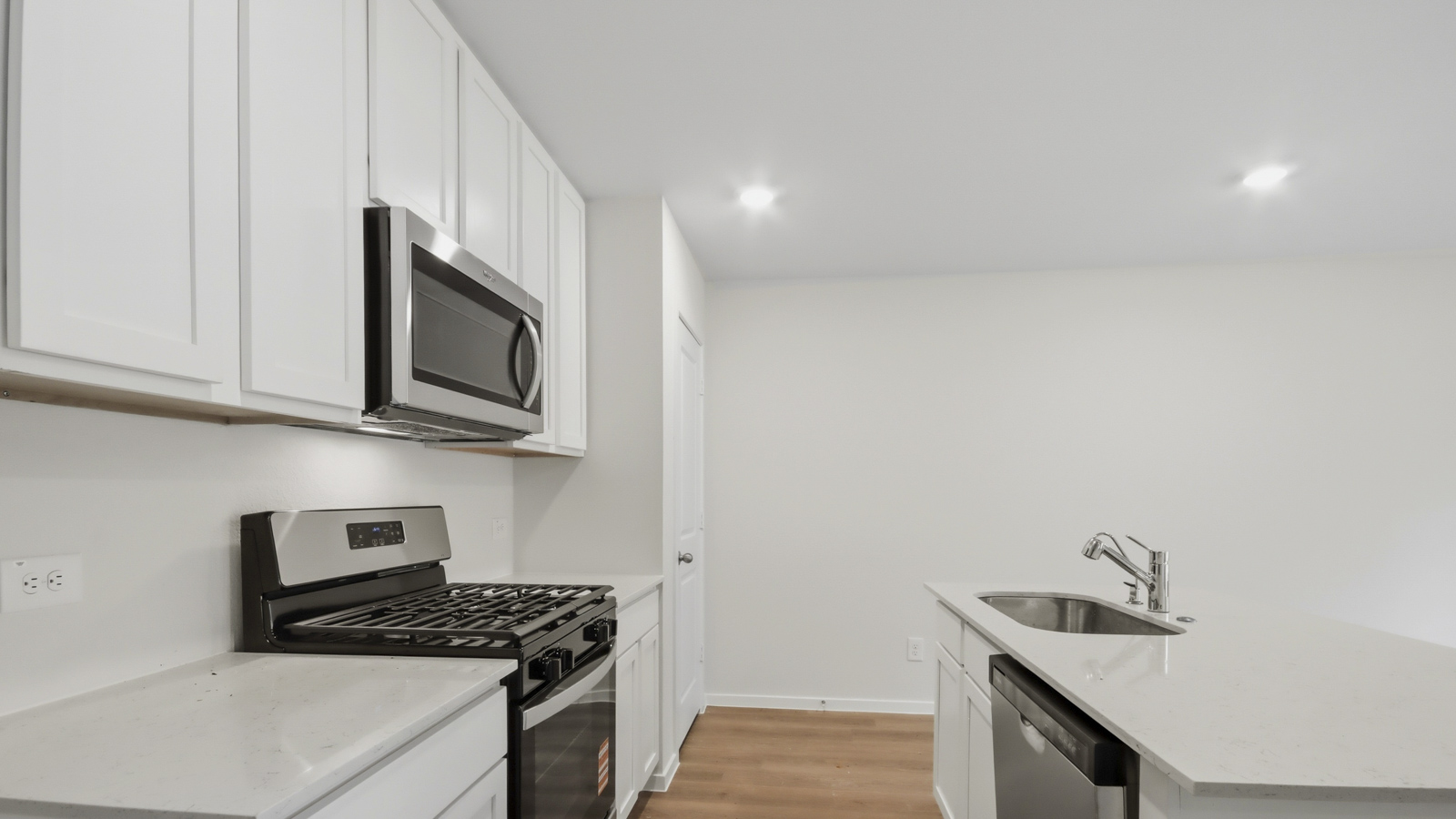 Kitchen with stainless steel appliances, quartz countertops and modern hardware and an island and vinyl floor