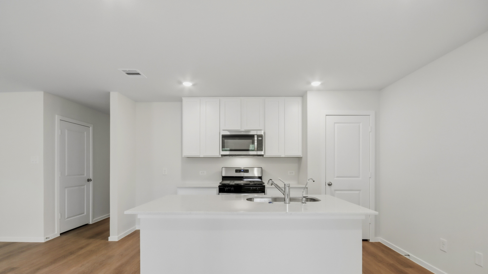 Kitchen with stainless steel appliances, quartz countertops and modern hardware and an island and vinyl floor
