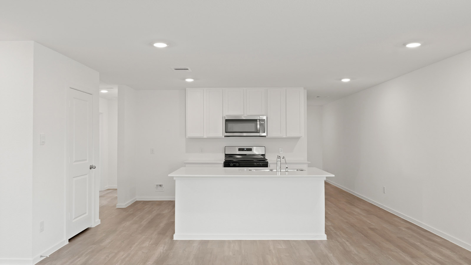 Open concept living, dining, and kitchen area with vinyl flooring and bright windows
