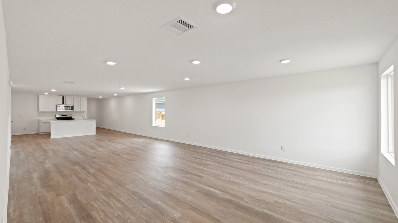 Open concept living, dining, and kitchen area with vinyl flooring and bright windows