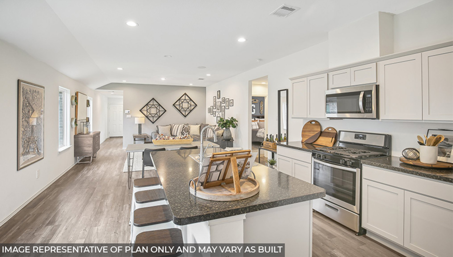 Open kitchen with an island, stainless steel appliances, white cabinets, white walls, and vinyl wood flooring.