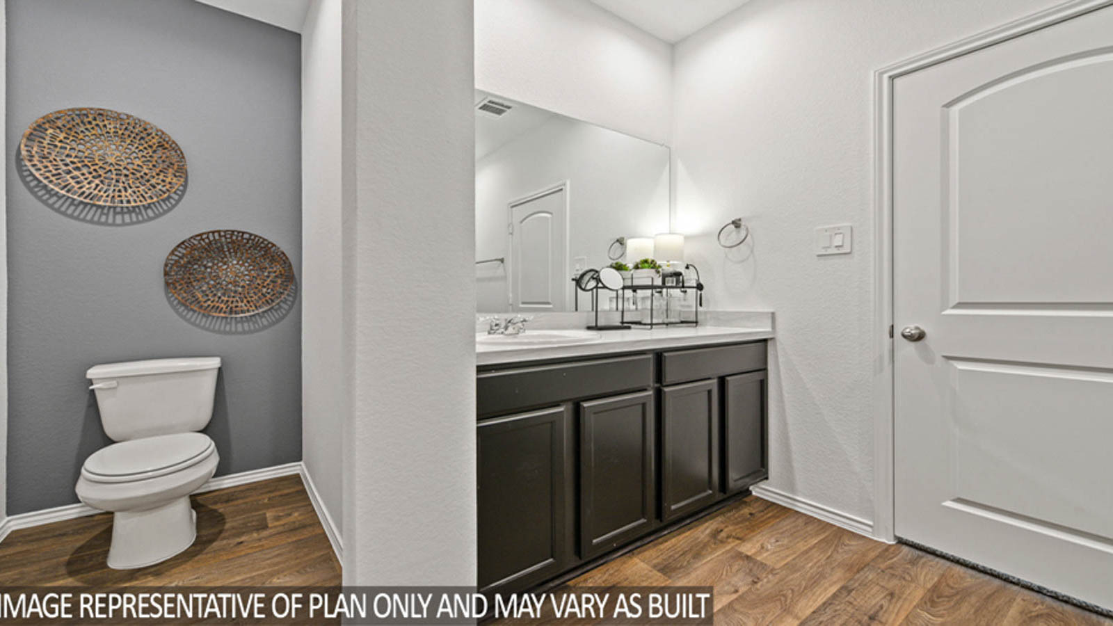 Primary bathroom with dual sinks, walk-in shower, storage shelves, white cabinets, white walls, and vinyl wood flooring.