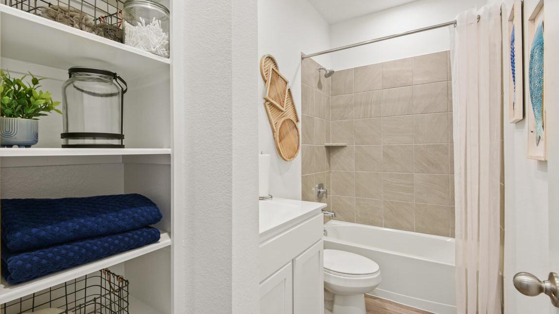 Secondary bathroom with a shower and tub combo, white walls, and vinyl wood flooring.