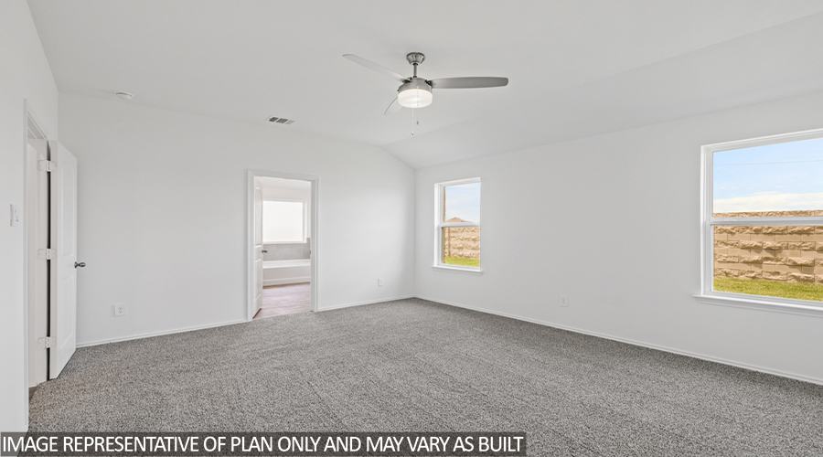 Primary bedroom with carpet flooring and bright windows.
