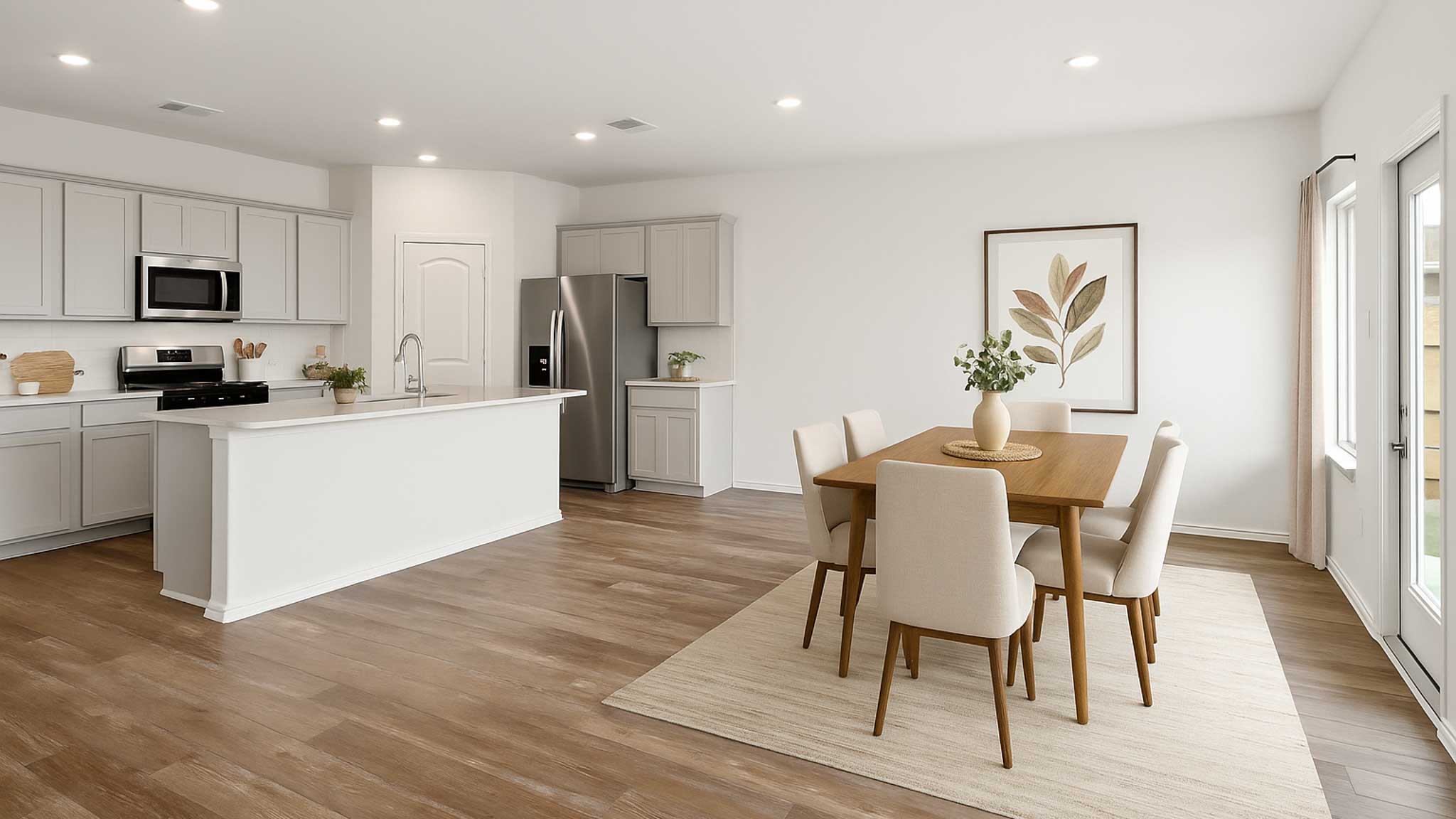 Staged open concept kitchen and dining area with vinyl flooring, bright windows, and stainless-steel appliances.