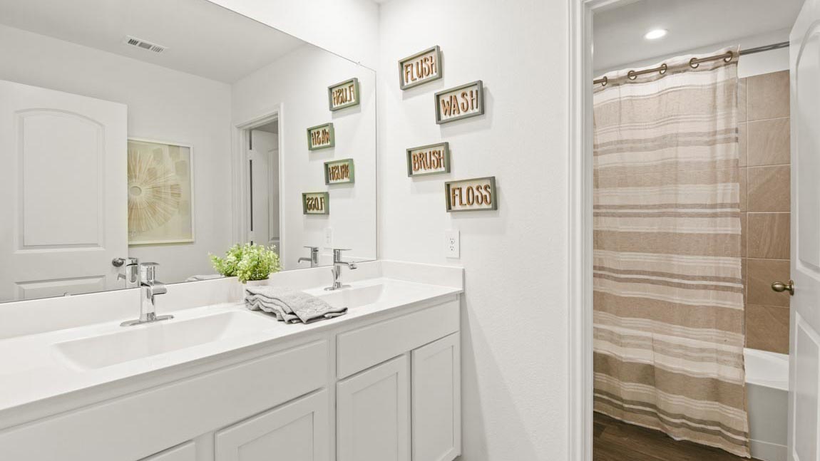 Staged secondary bathroom with a double sink and a separate toilet room consisting of a tile tub/shower combo and a toilet.