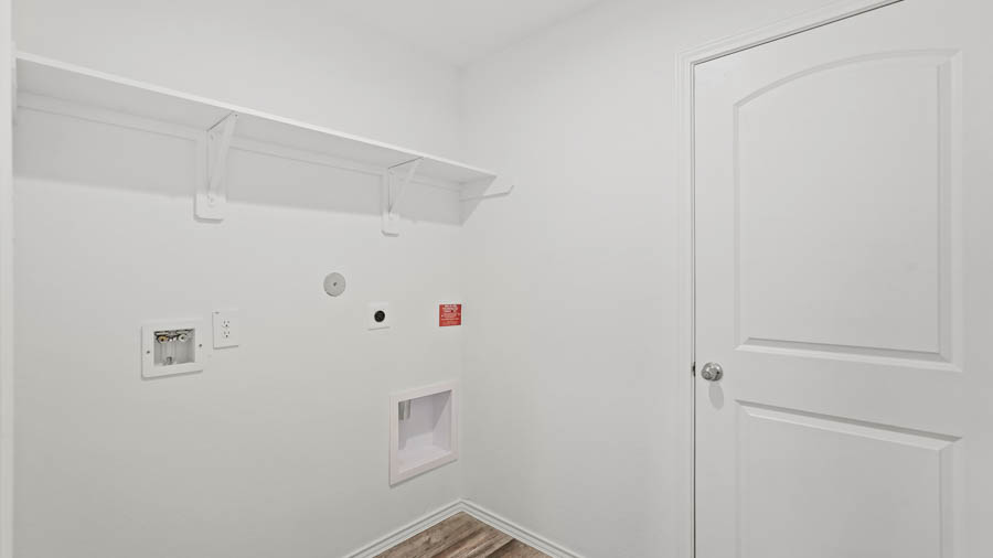 Utility room with vinyl flooring and overhead storage space.