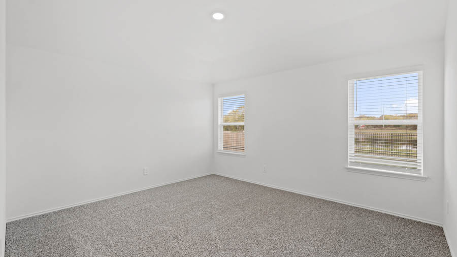 Primary bedroom with carpet flooring and bright windows.