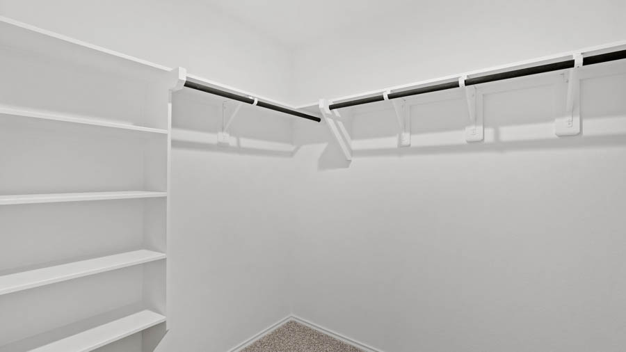 Primary bedroom walk-in closet with overhead storage space.
