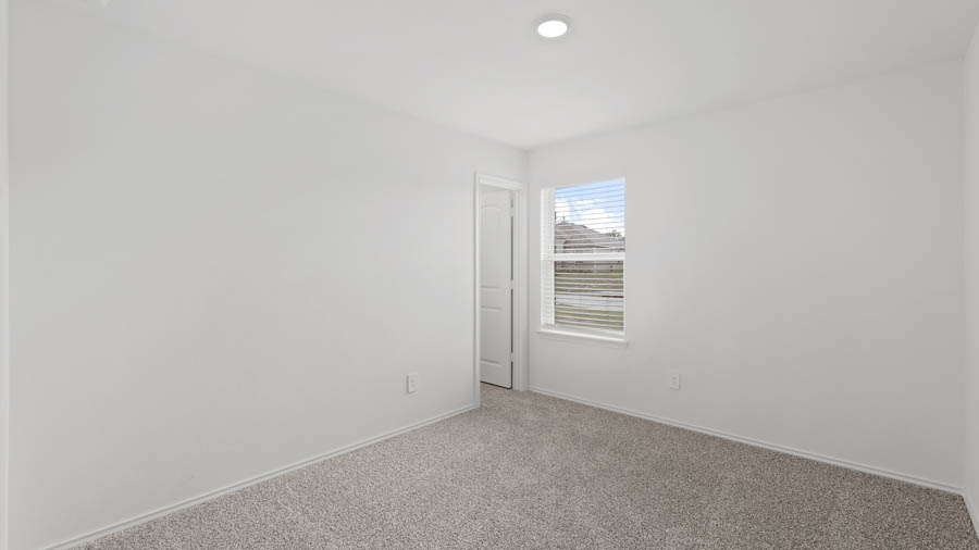 Secondary bedroom with carpet flooring and a bright window.