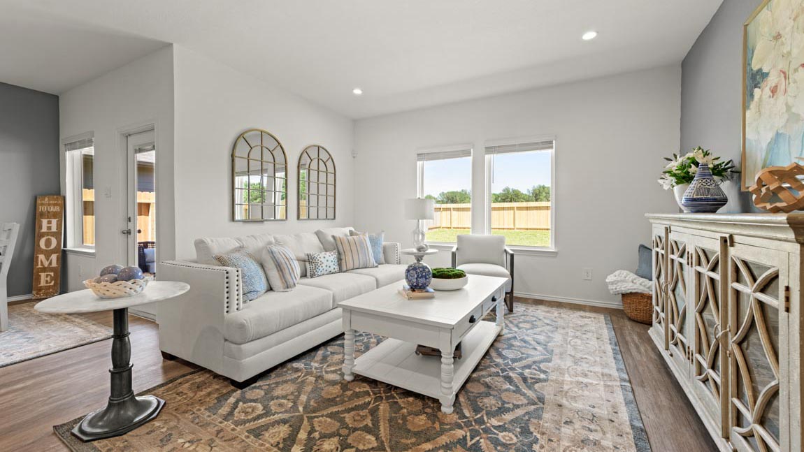 Living room in this new construction home features natural light, with connective flow to the kitchen, dining areas