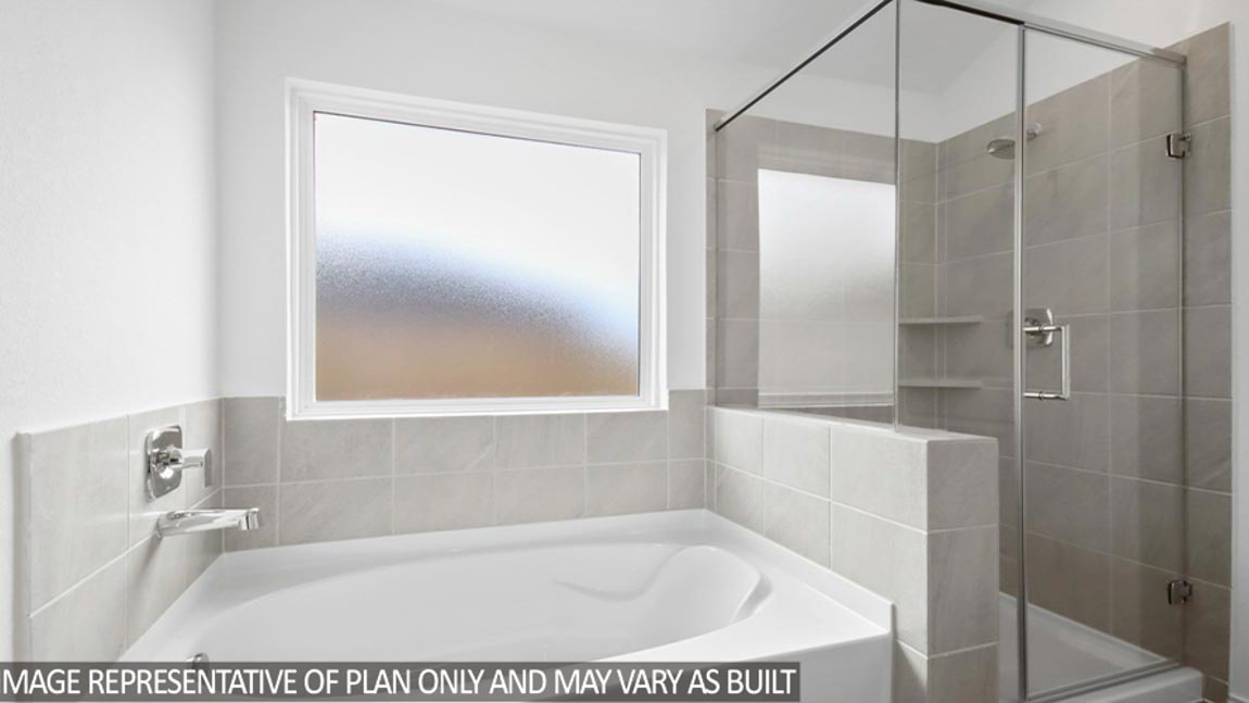 Primary bathroom with a tile tub, a frosted window, and a standing shower with a glass door.