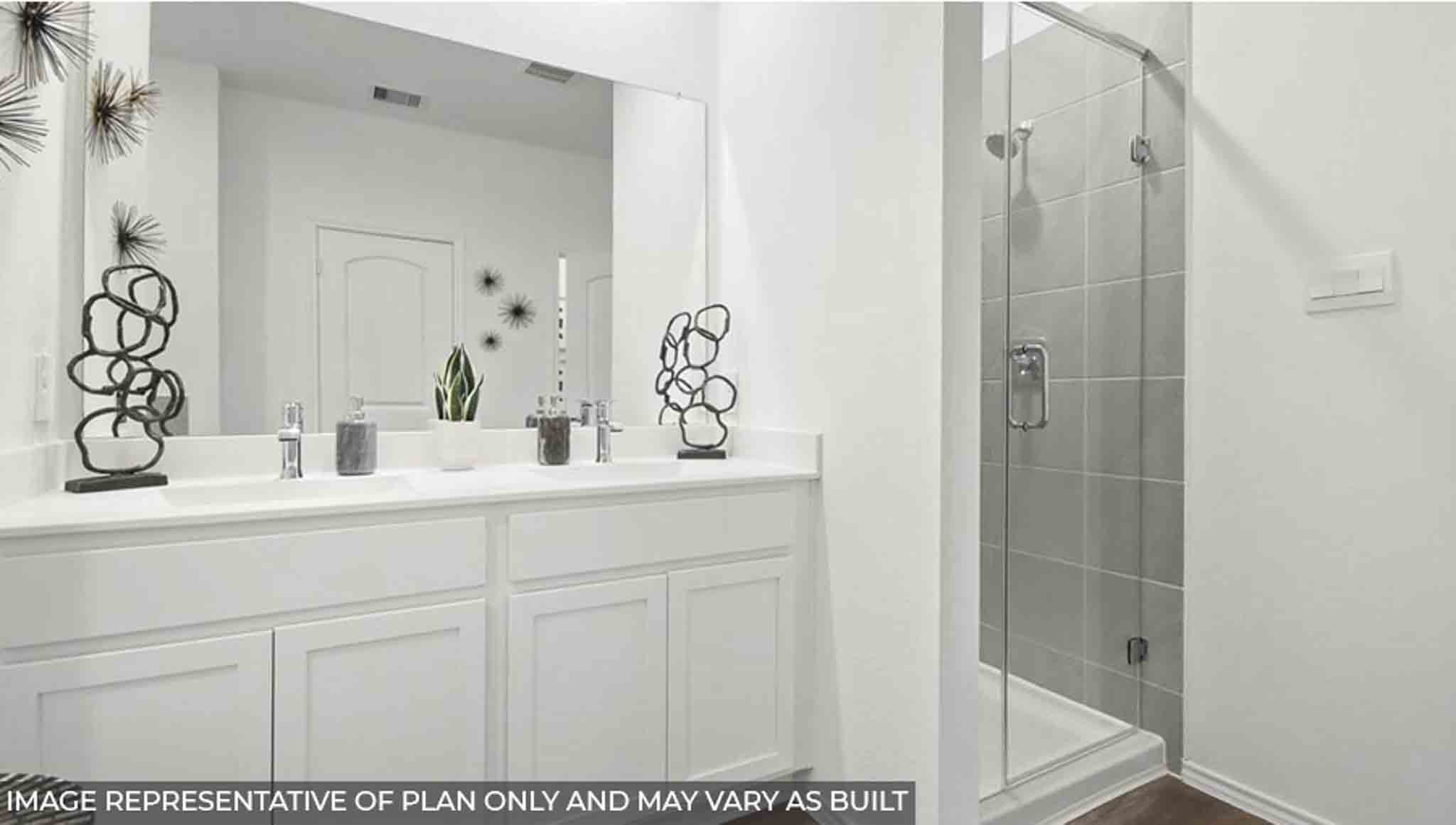 Primary bathroom with a double sink, a separate toilet room, and a standing shower.