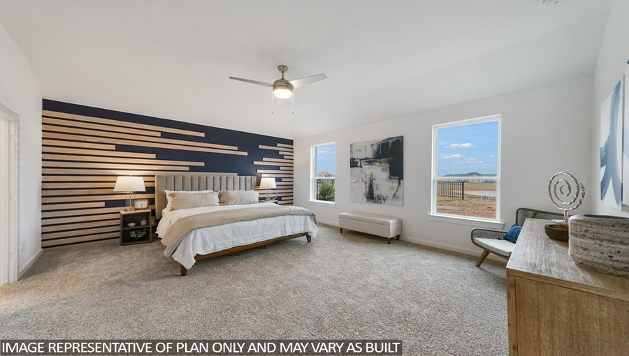 Staged primary bedroom with carpet flooring and bright windows.