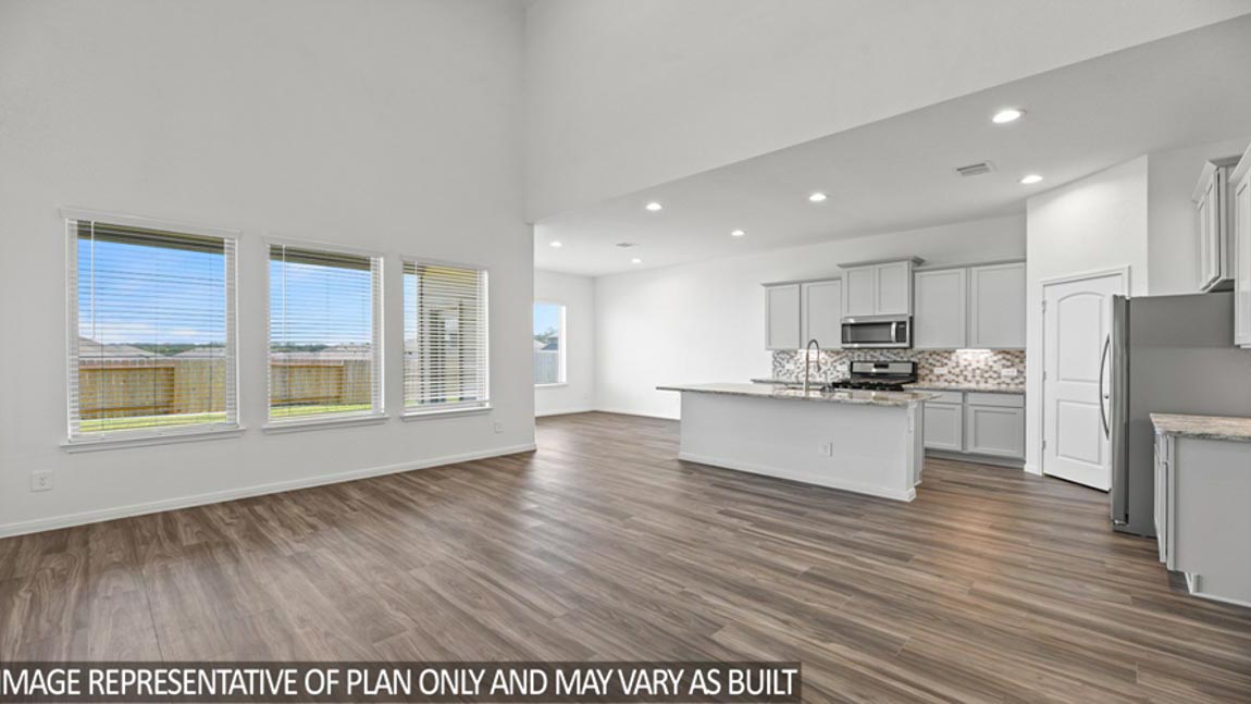Open concept living and dining area with vinyl flooring and bright windows.