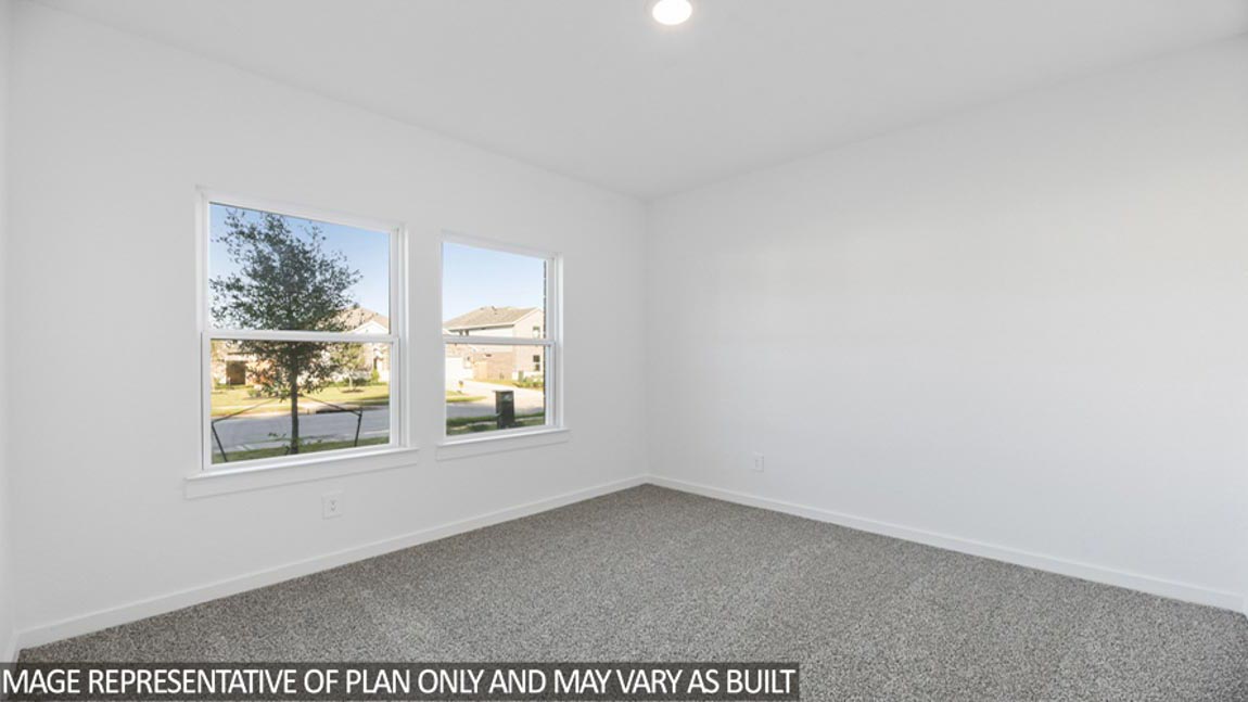 Secondary bedroom with carpet flooring and bright windows.