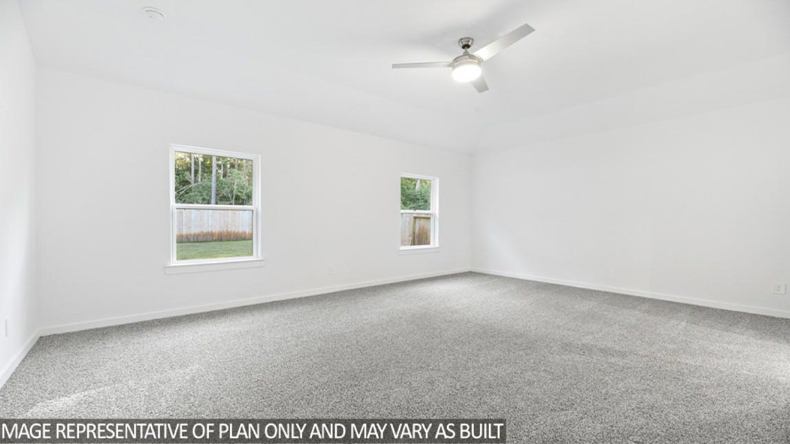 Primary bedroom with carpet flooring, a ceiling fan, and bright windows.